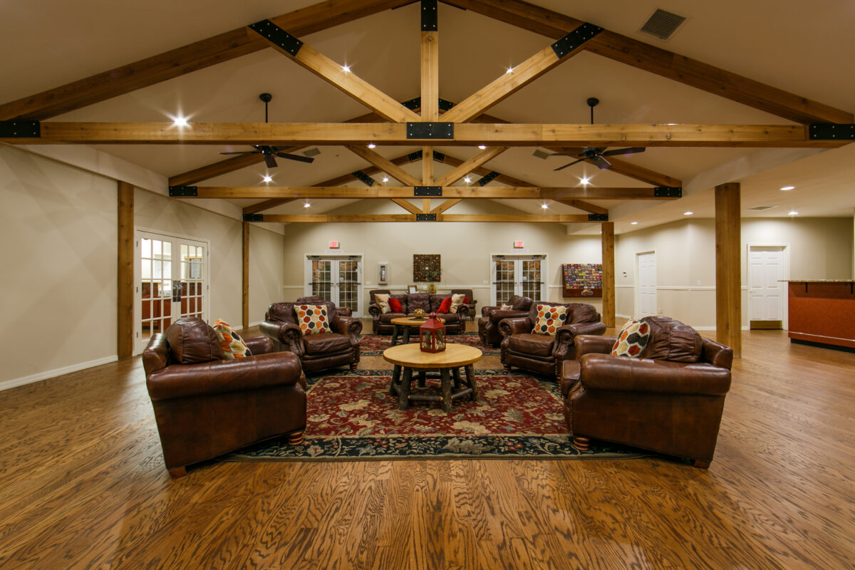 A roof with pillars and a seating area, with a table and brown leather chairs in the center.