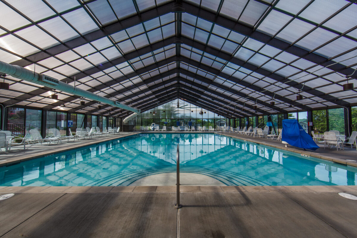 A blue hotel pool beneath a pointed ceiling.