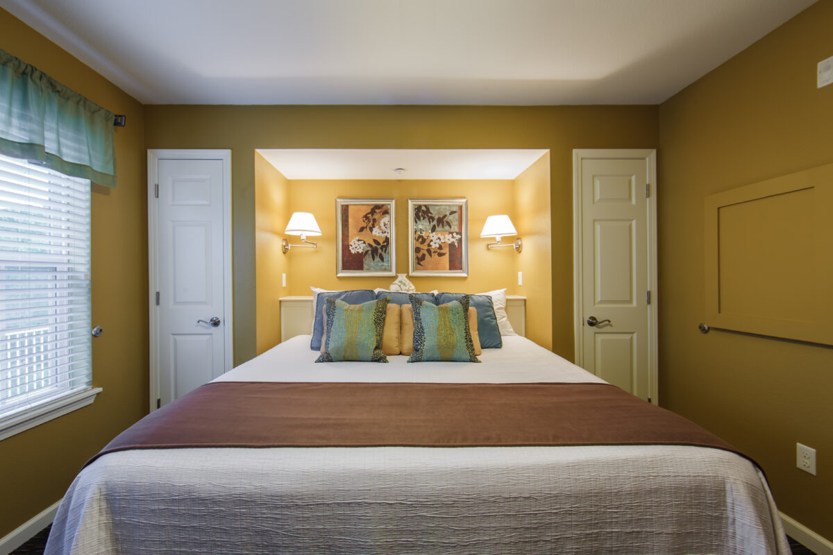 A furnished bedroom with a bed, furniture and artwork.