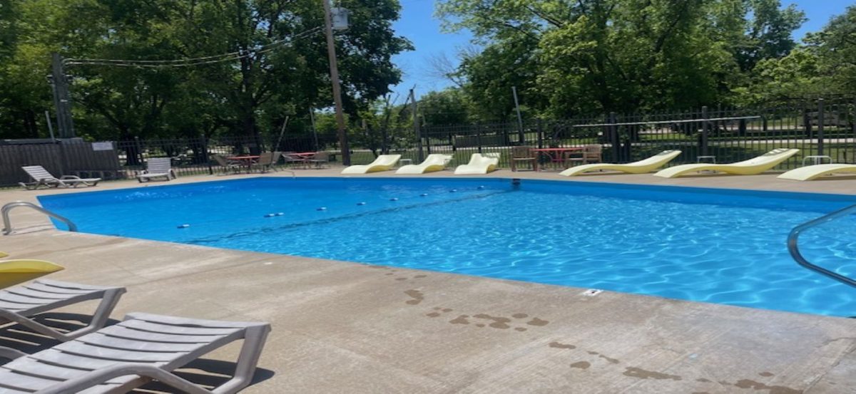 A pool, concrete walkway and patio furniture.