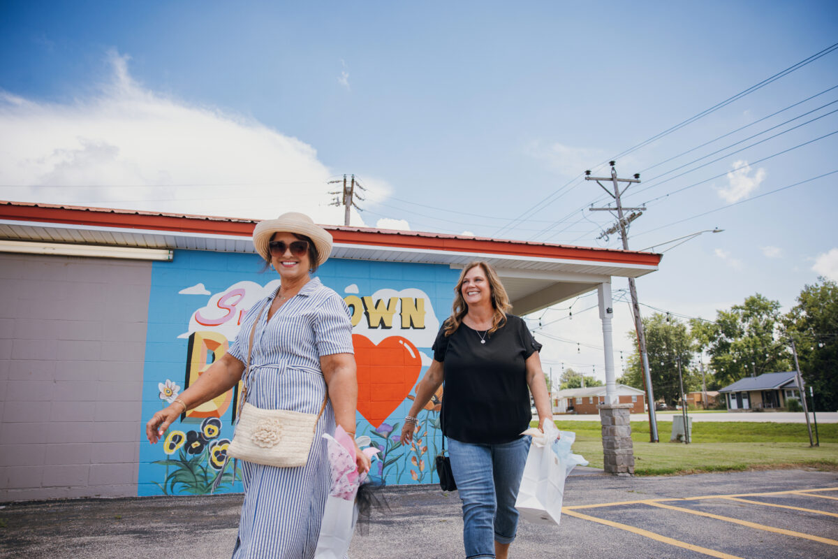 Two women walking in front of a mural.