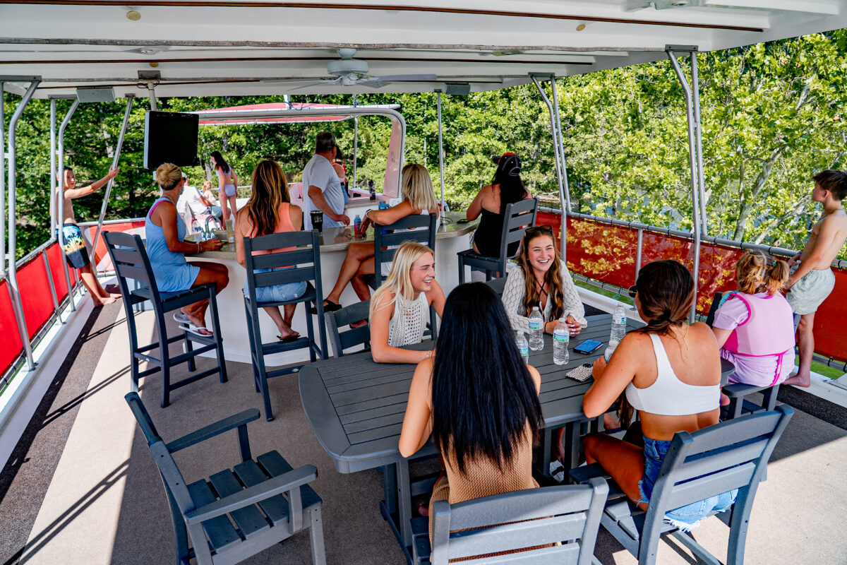 Several people lounge on chairs atop a houseboat.