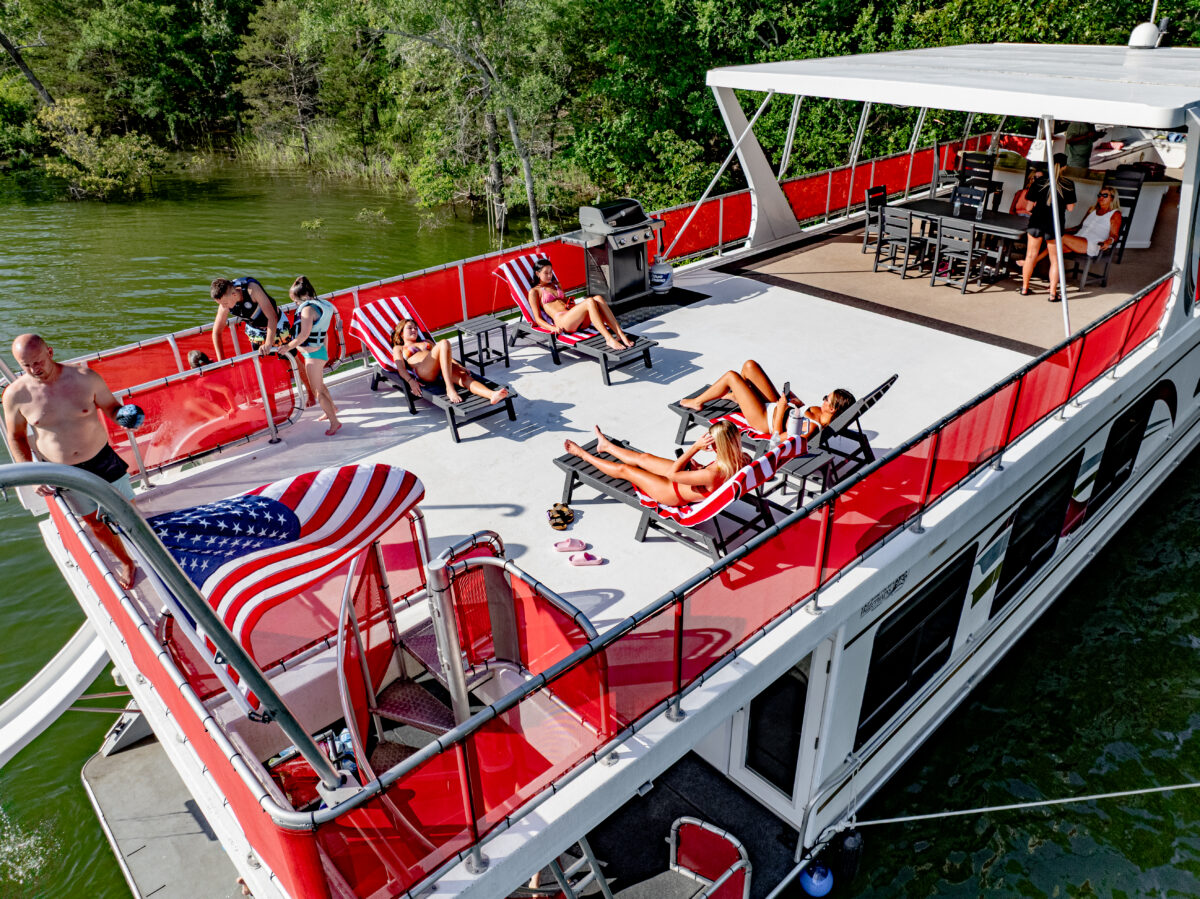 Several people lounge on chairs atop a houseboat.
