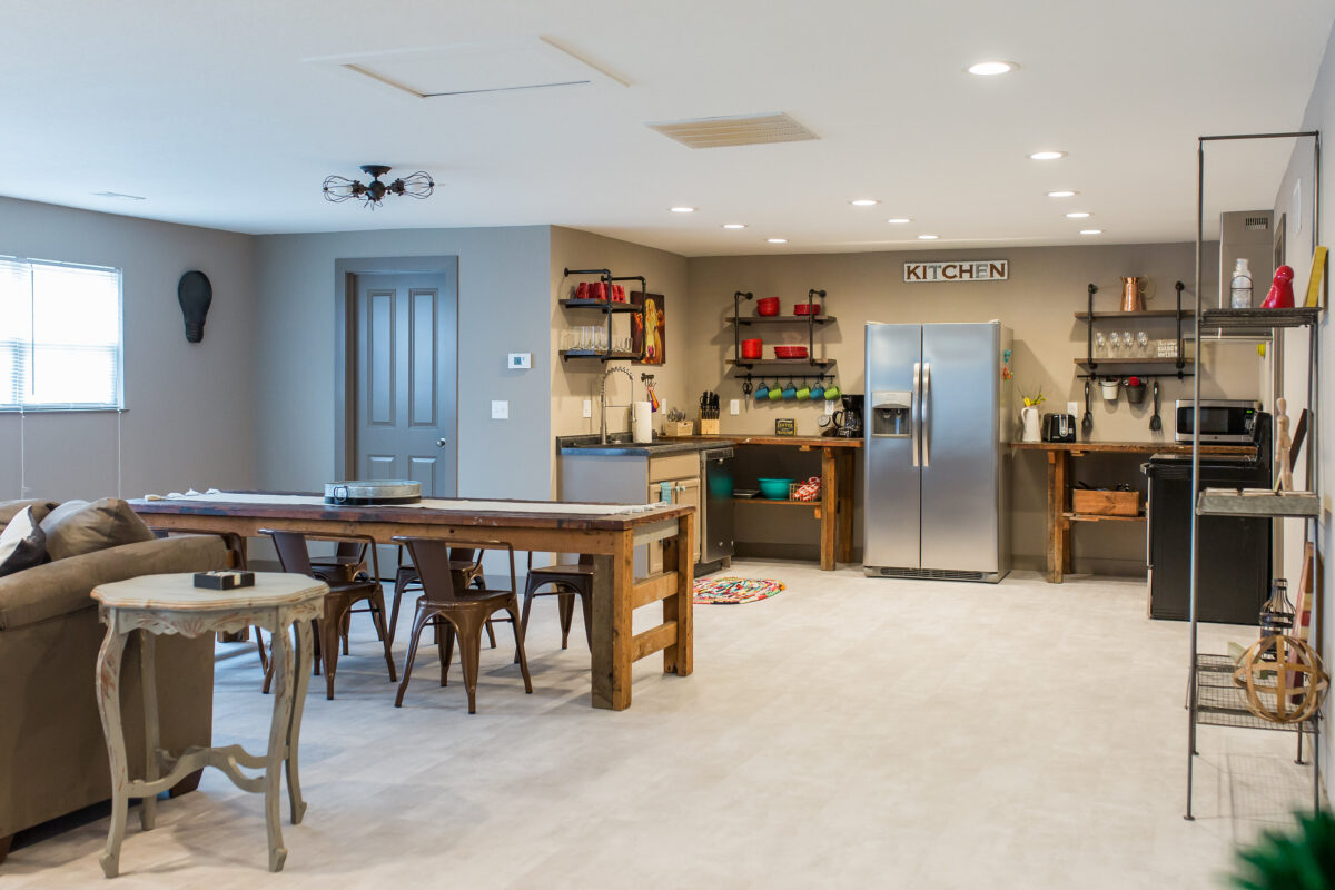 A furnished dining room and kitchen, including a table and chairs and shelving.