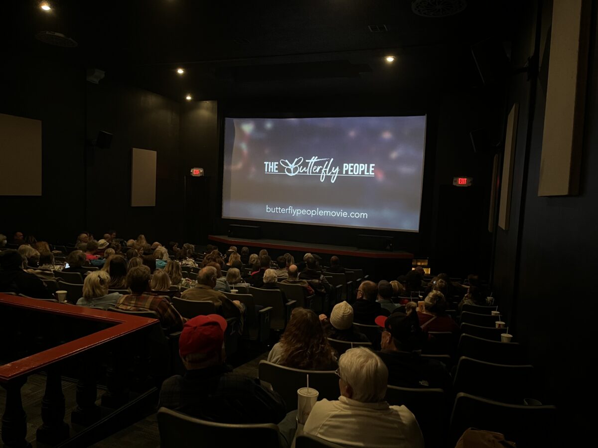 Viewers watch a film on a large screen in a theater.