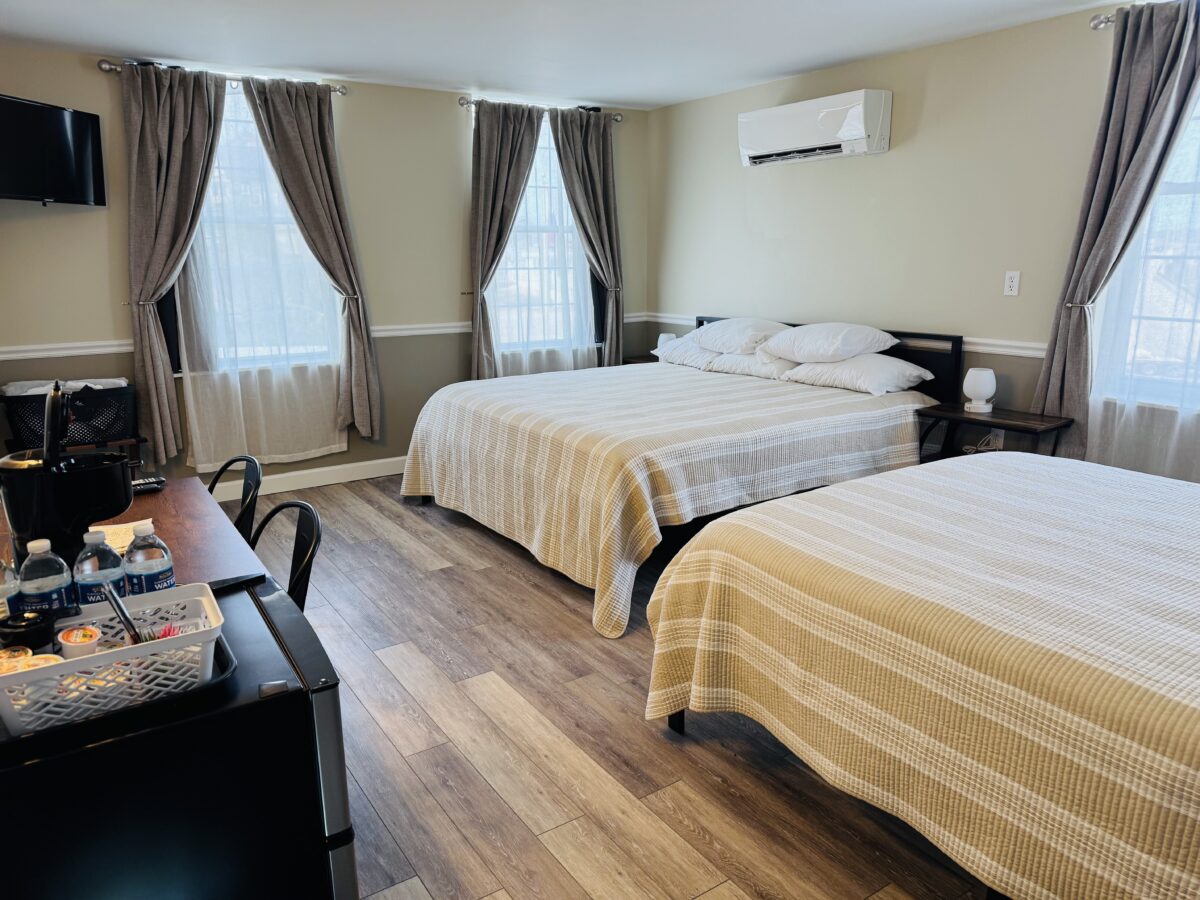 Two beds in a bedroom, with several windows looking out.