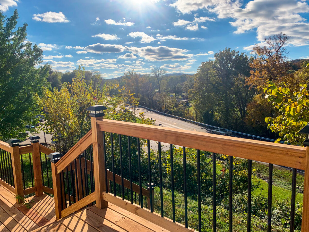 The view of right blue skies, clouds and trees from a wooden deck.