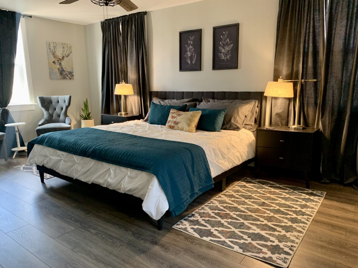 A bedroom with curtains, a rug and a large bed.
