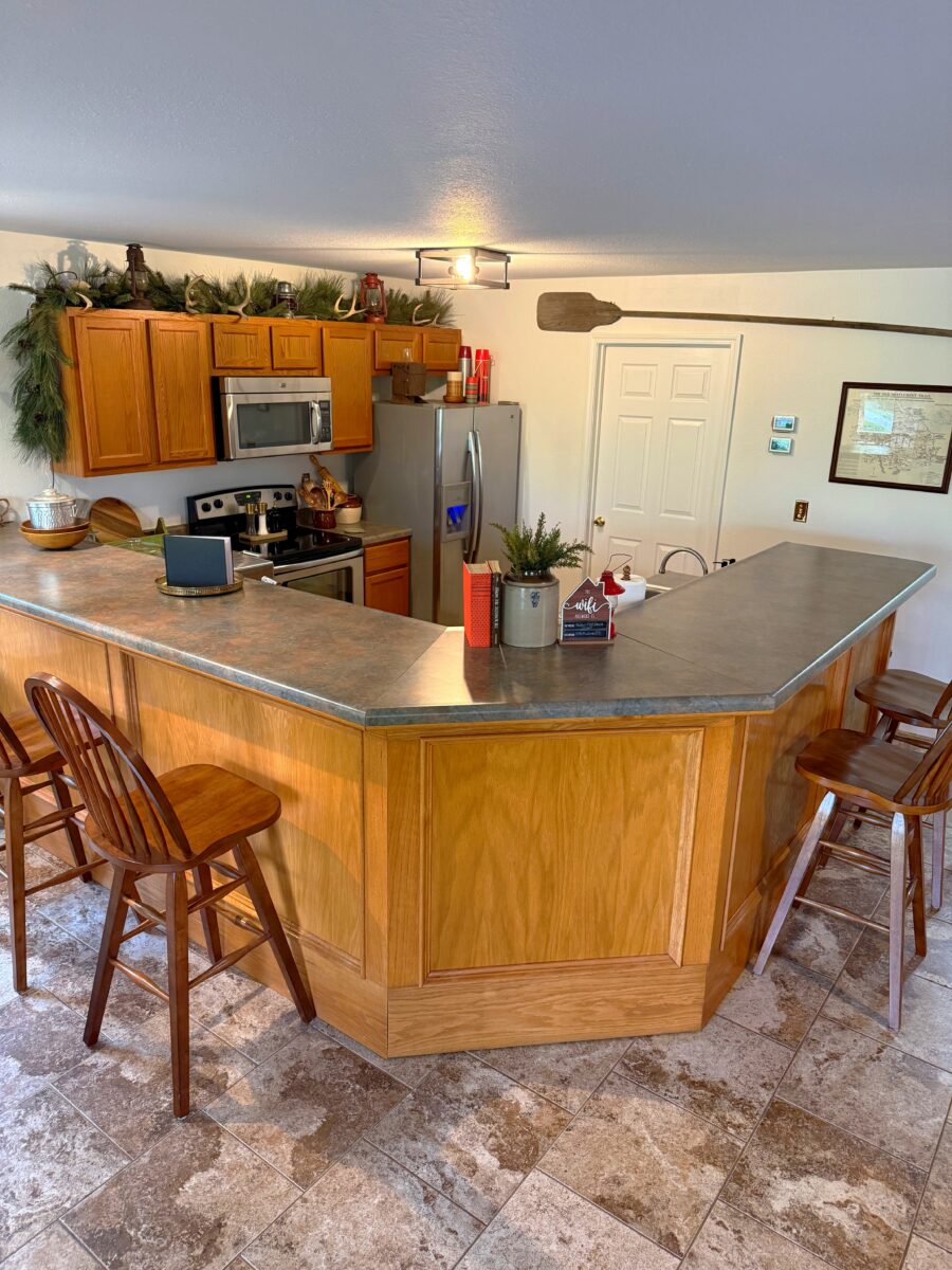 A furnished kitchen with appliances and a counter-bar, plus chairs.