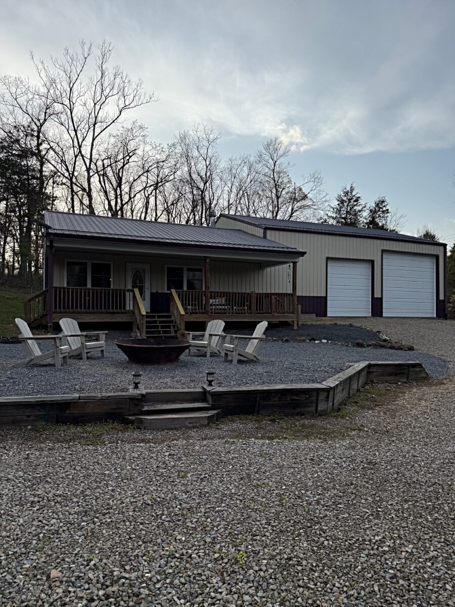 A fire pit and white chairs outside of a rental house.