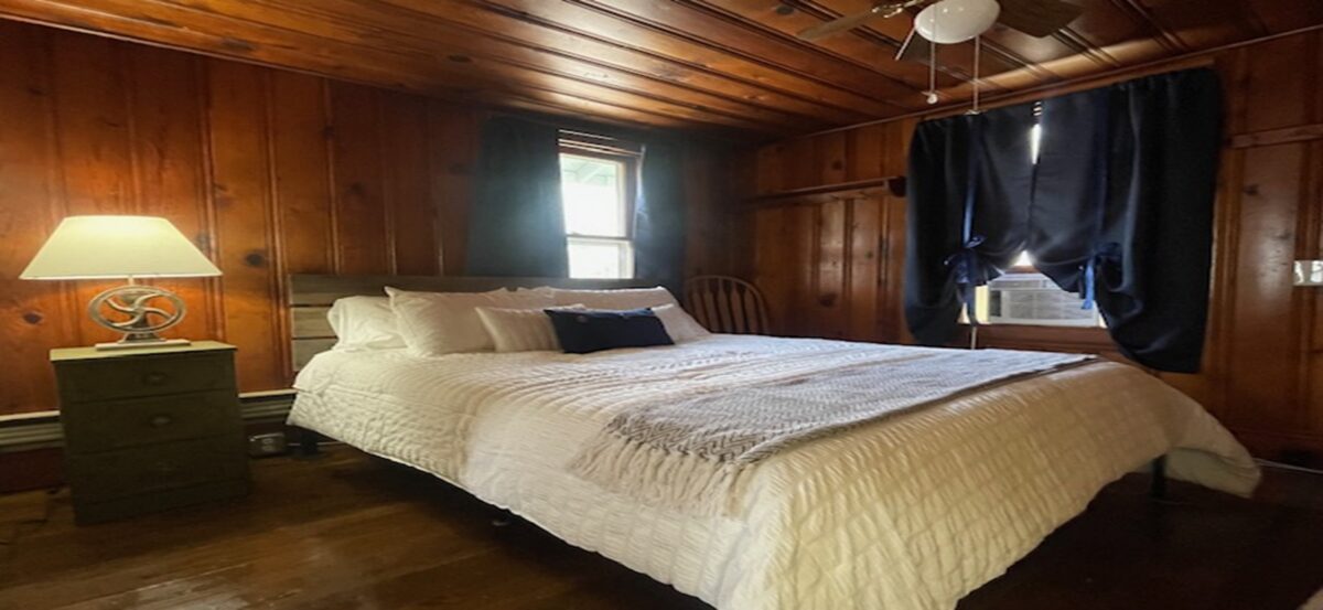 Interior of a bedroom with brown furnishings and white sheets.