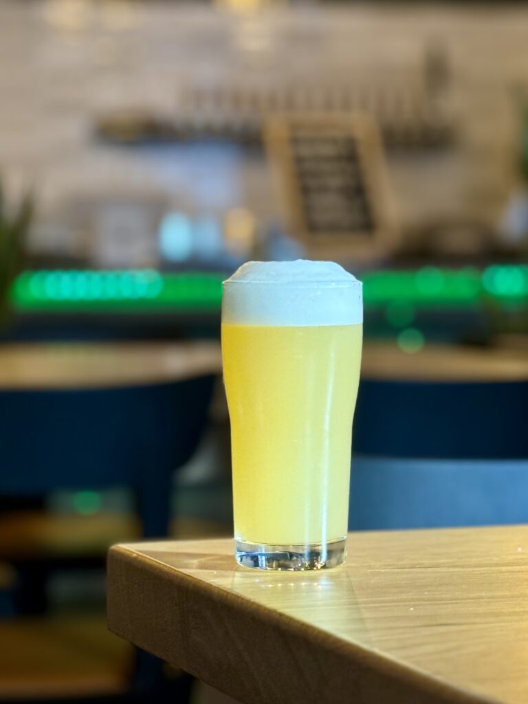 A frothy beer on a wooden table.