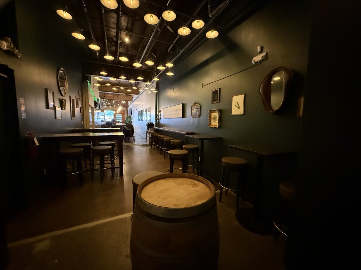 A bar room with tables, chairs, stools and a barrel.