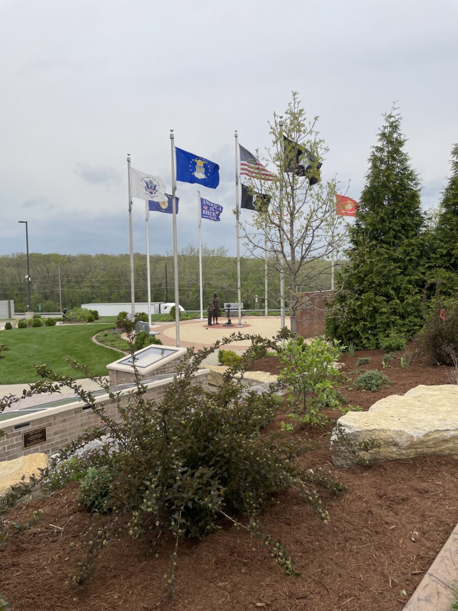 Various flags hoisted high as part of a veterans memorial.