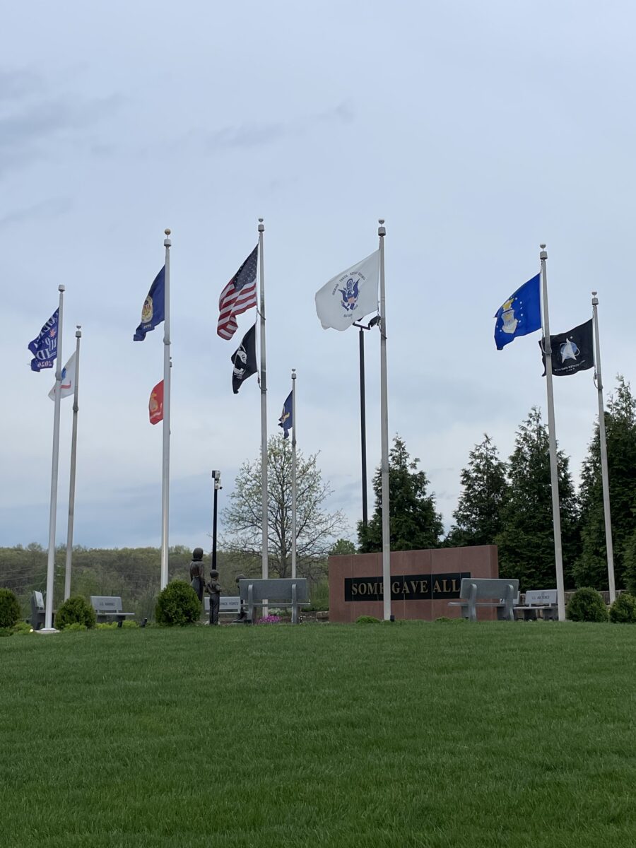 Various flags hoisted high as part of a veterans memorial.