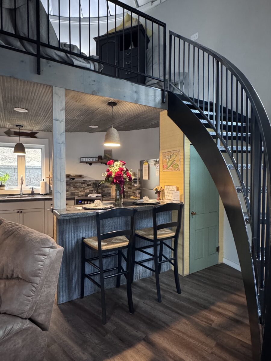 A counter and chairs nestled beneath a staircase and balcony.