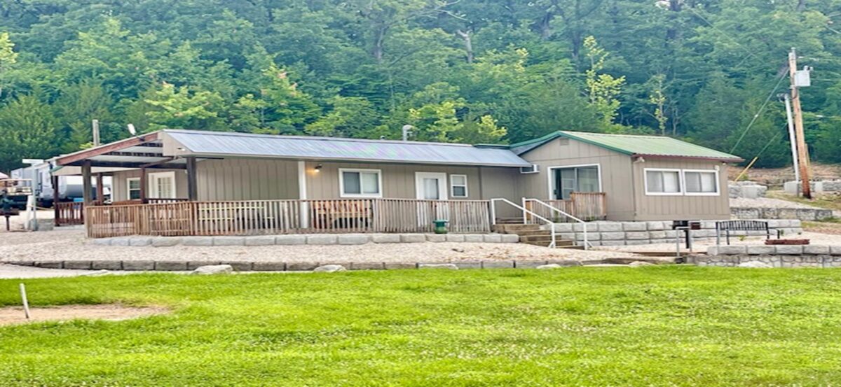 The outside of cabins amidst bright green grass and trees.