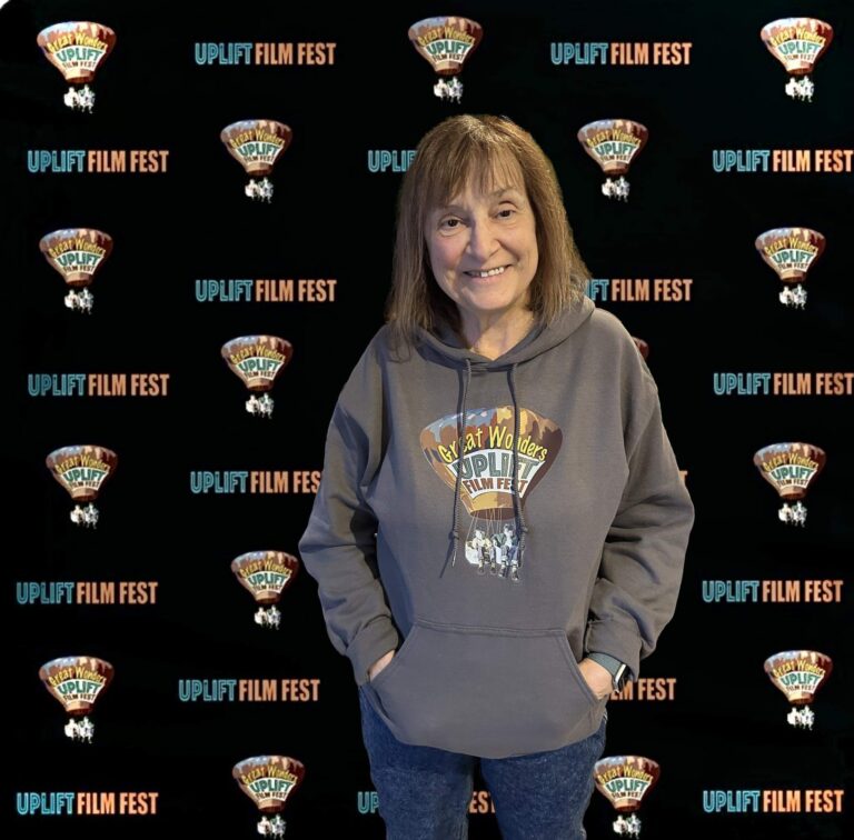 A woman wearing merchandise for a film festival poses in front of a display wall.