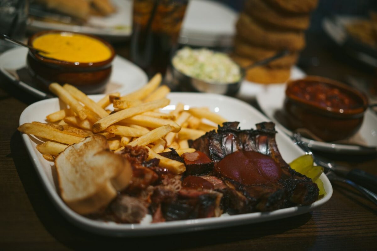 A jam-packed plate of barbecue with meat, bread and French fries. 