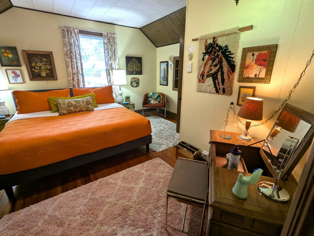 A bedroom with orange dressing and vintage furnishings.