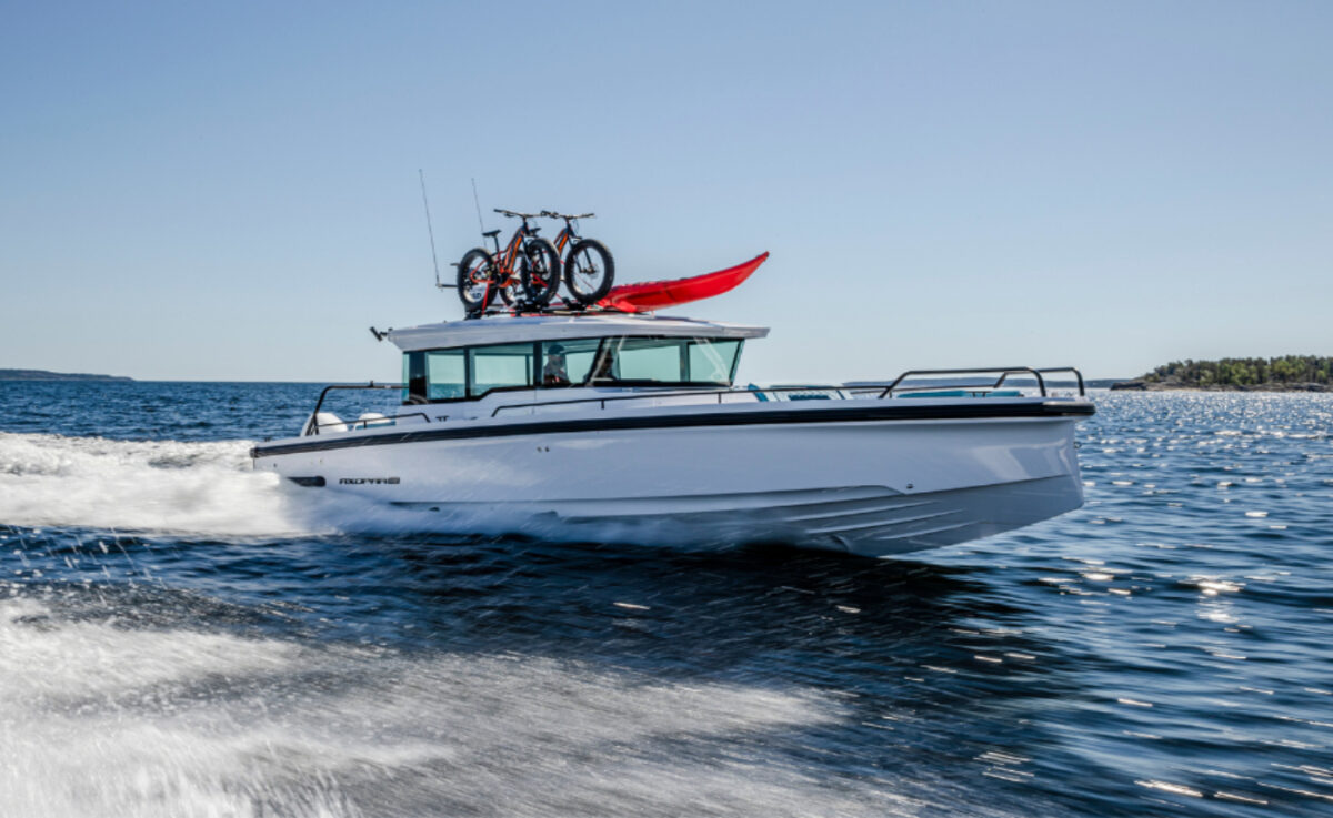 A boat with a red flag and bikes on top on the water.