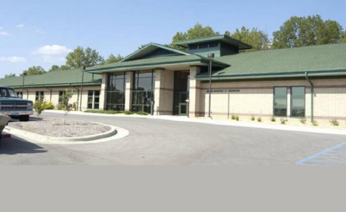 The exterior of a building, tan with green roofing.