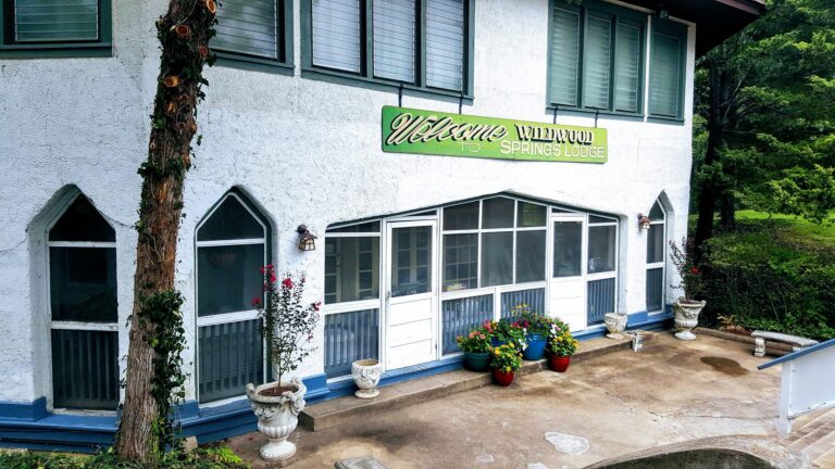The entrance to a lodge, a white building with a green sign.