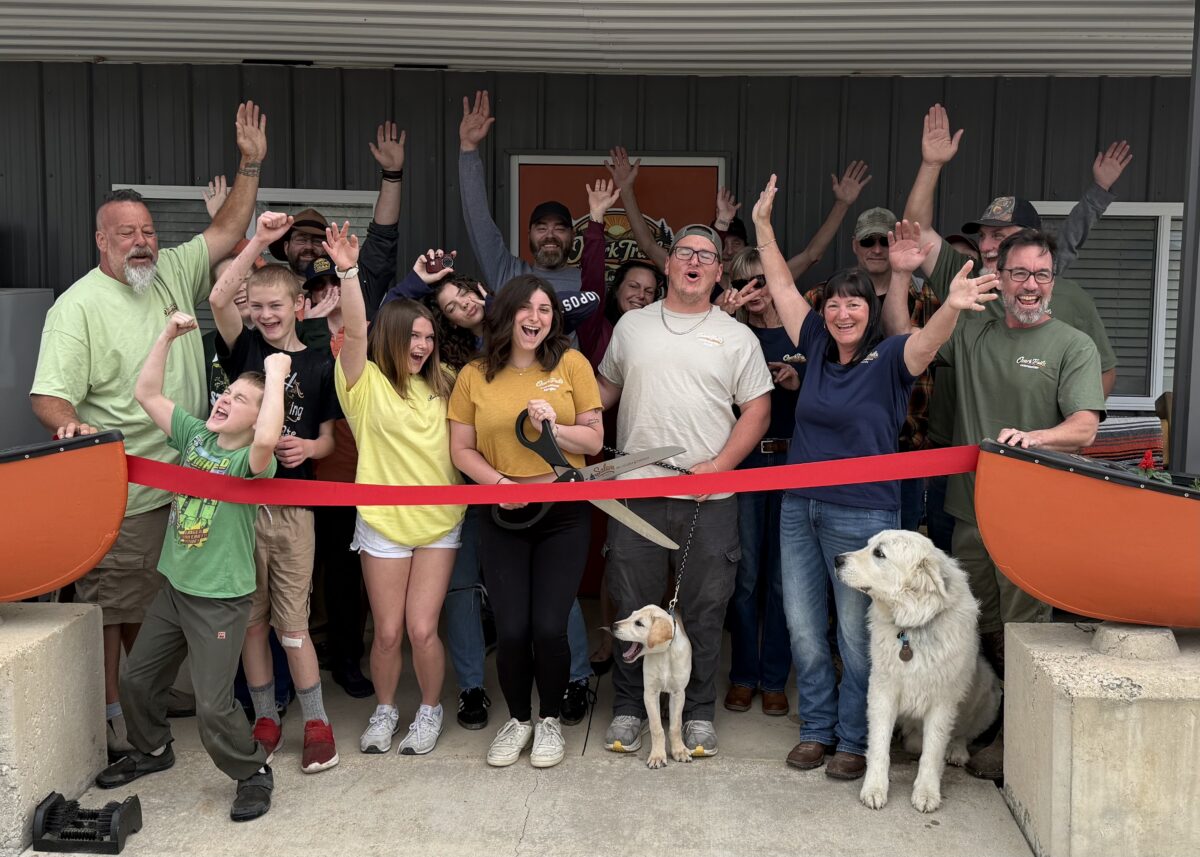 Several people pose during a ribbon cutting outdoors.