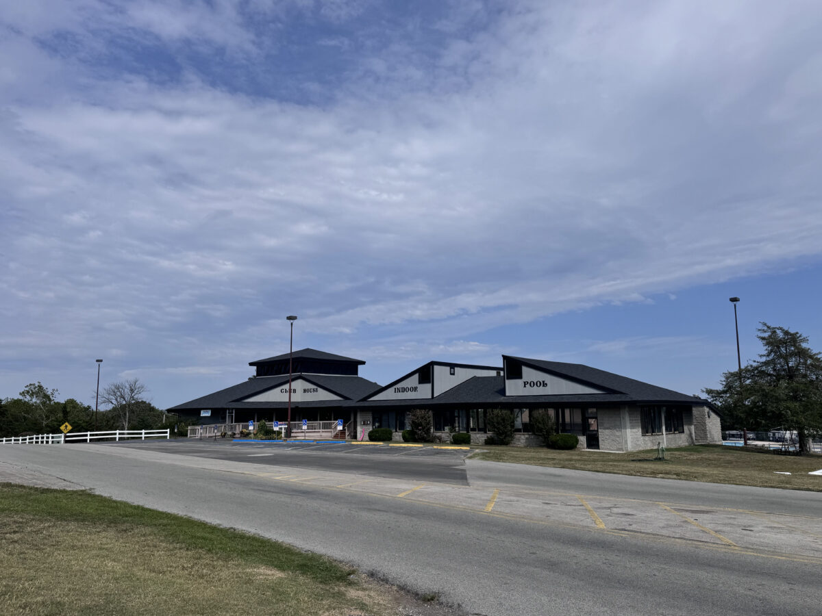 The exterior of a grey clubhouse from across the street on a cloudy day.