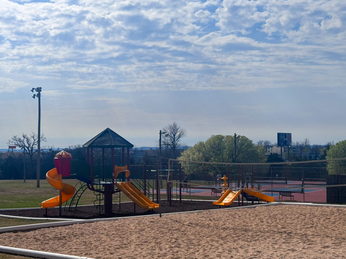 A playground outside of a clubhouse with colorful equipment.