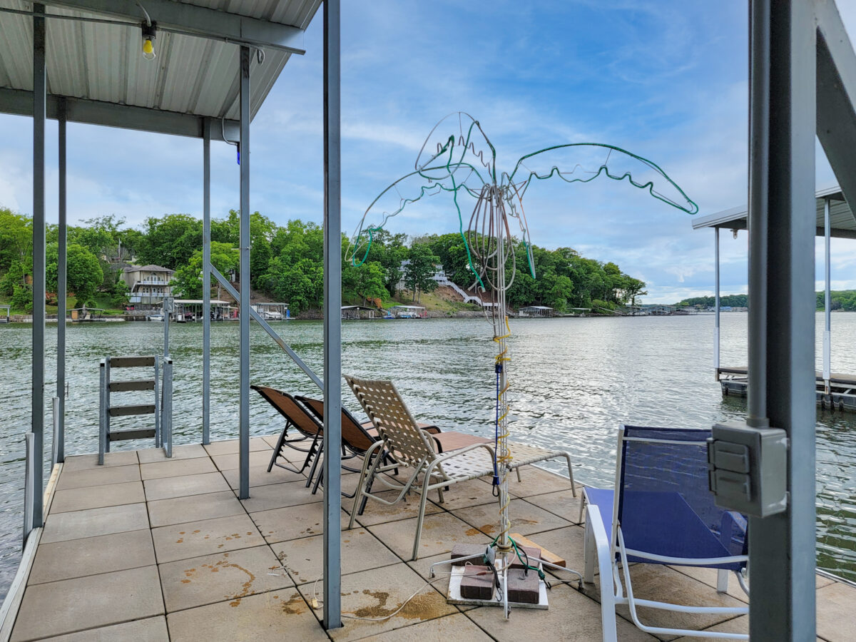 A concrete dock with a table and chairs near a lake.