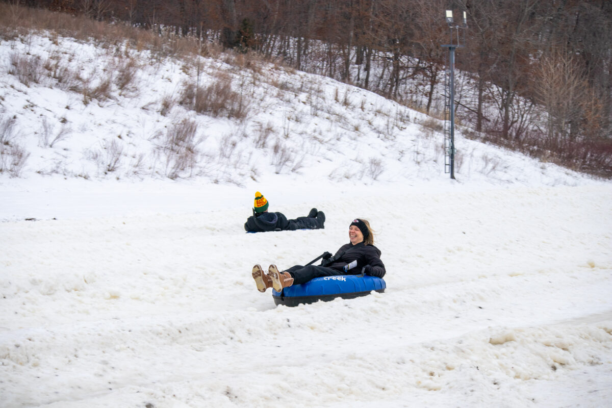 People tubing down a snowy hill.