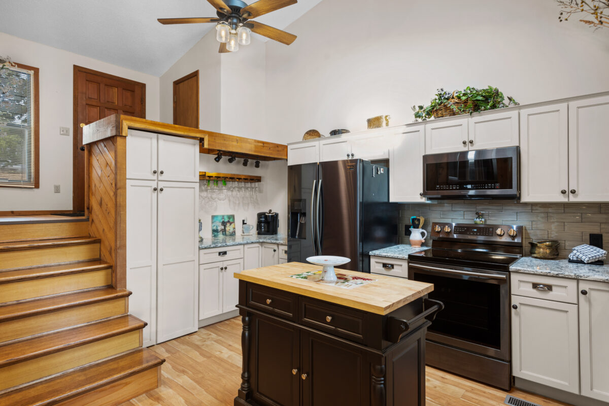 A kitchen with appliance and stairs heading upward.