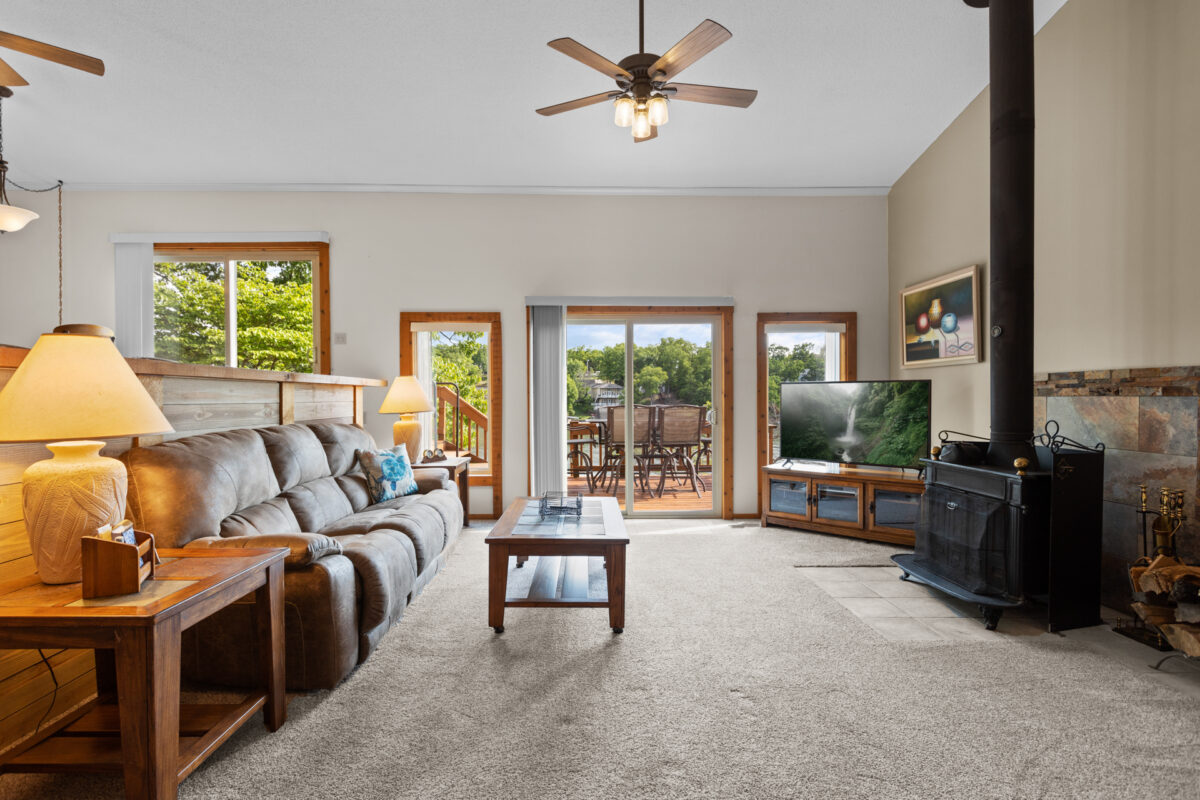 A living room with furniture and lighting and windows looking out toward a lake.