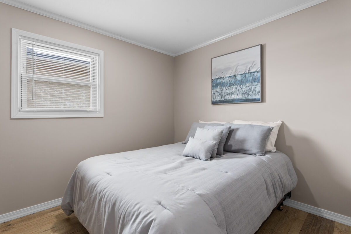 A bedroom with window and a painting on the wall.