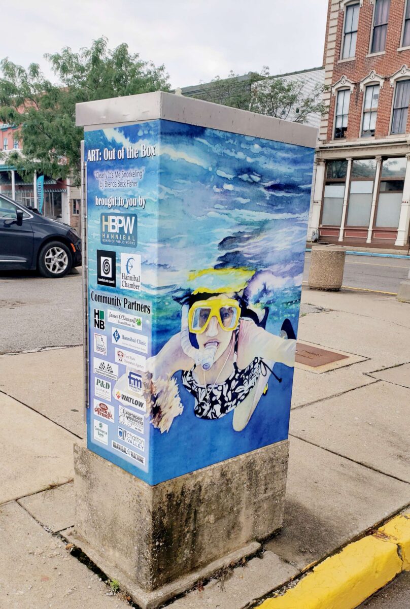 A wrapped concrete box depicting someone in the water.