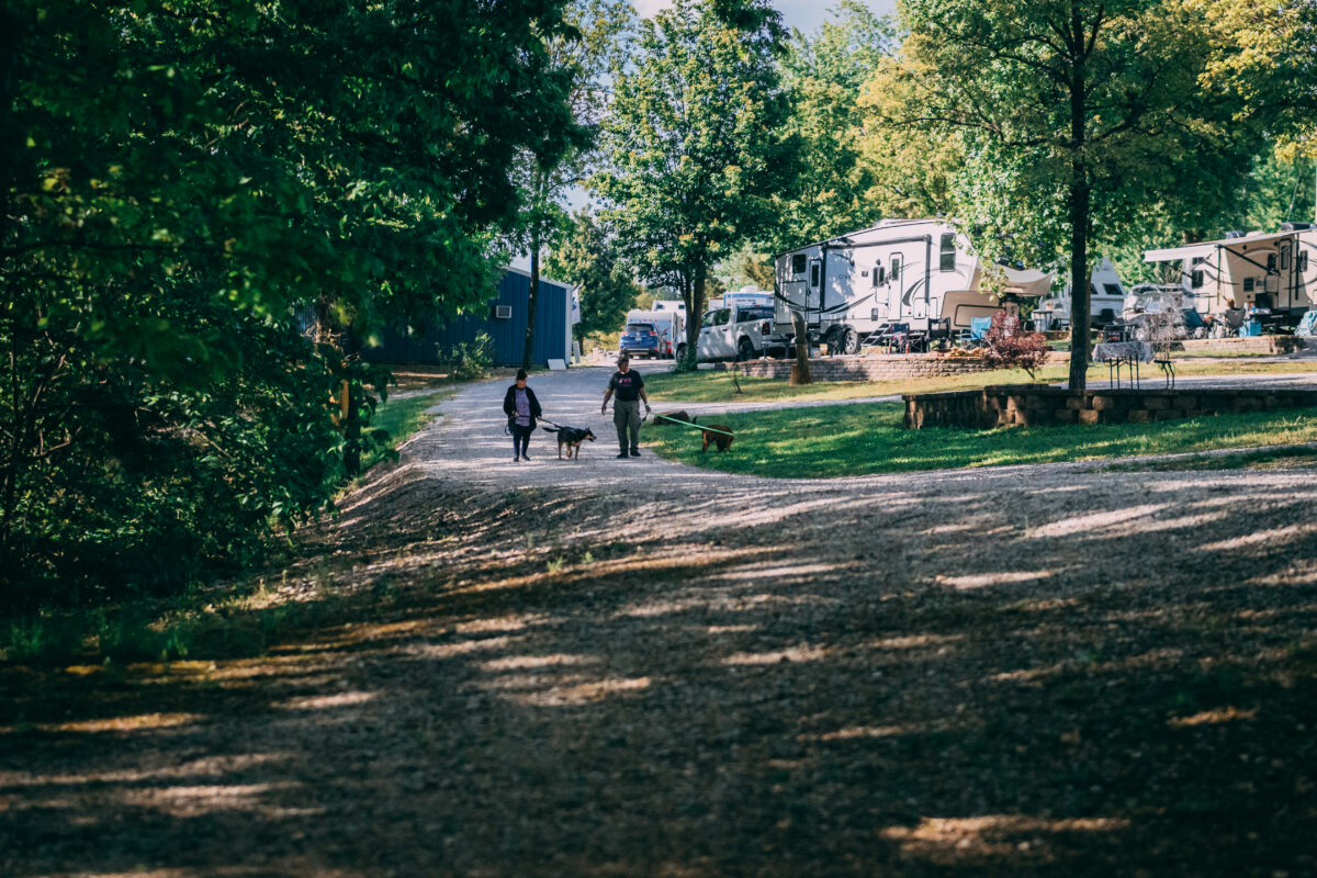 Two people in the distance walking through a campground with RVs parked nearby.