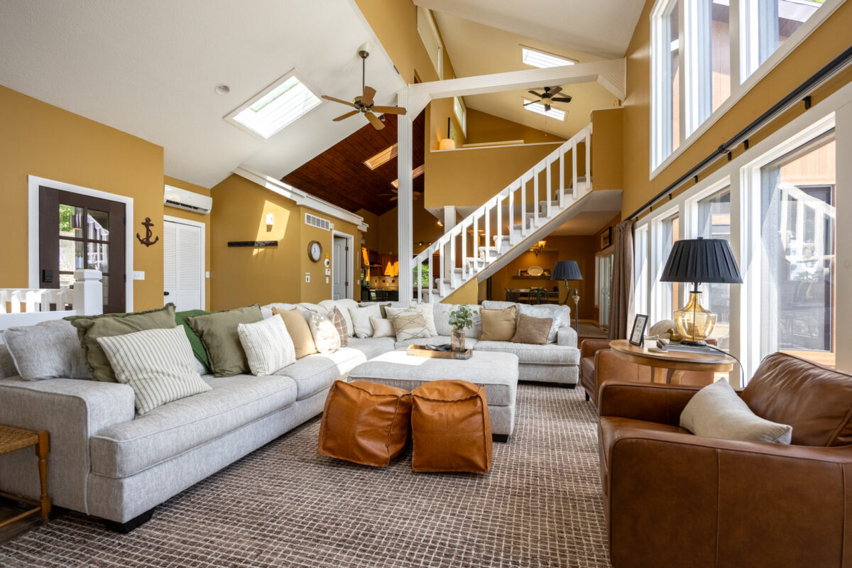 A furnished living room space with natural lighting and stairs leading upward.