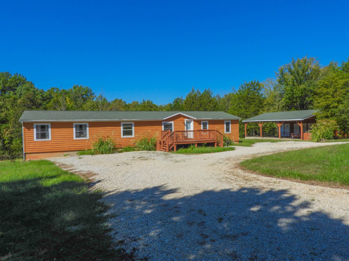 The exterior of cabins in a wooded area with a pond.