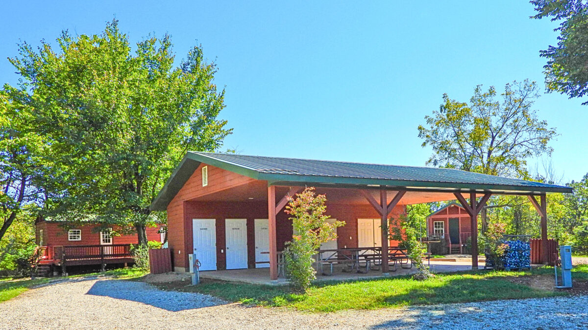The exterior of cabins in a wooded area with a pond.