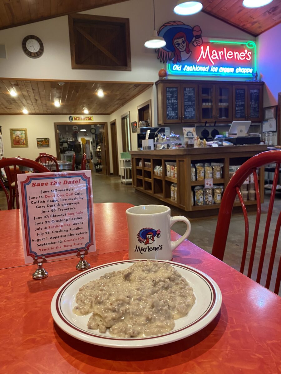 Breakfast food on a plate next to a mug and a red tabletop.