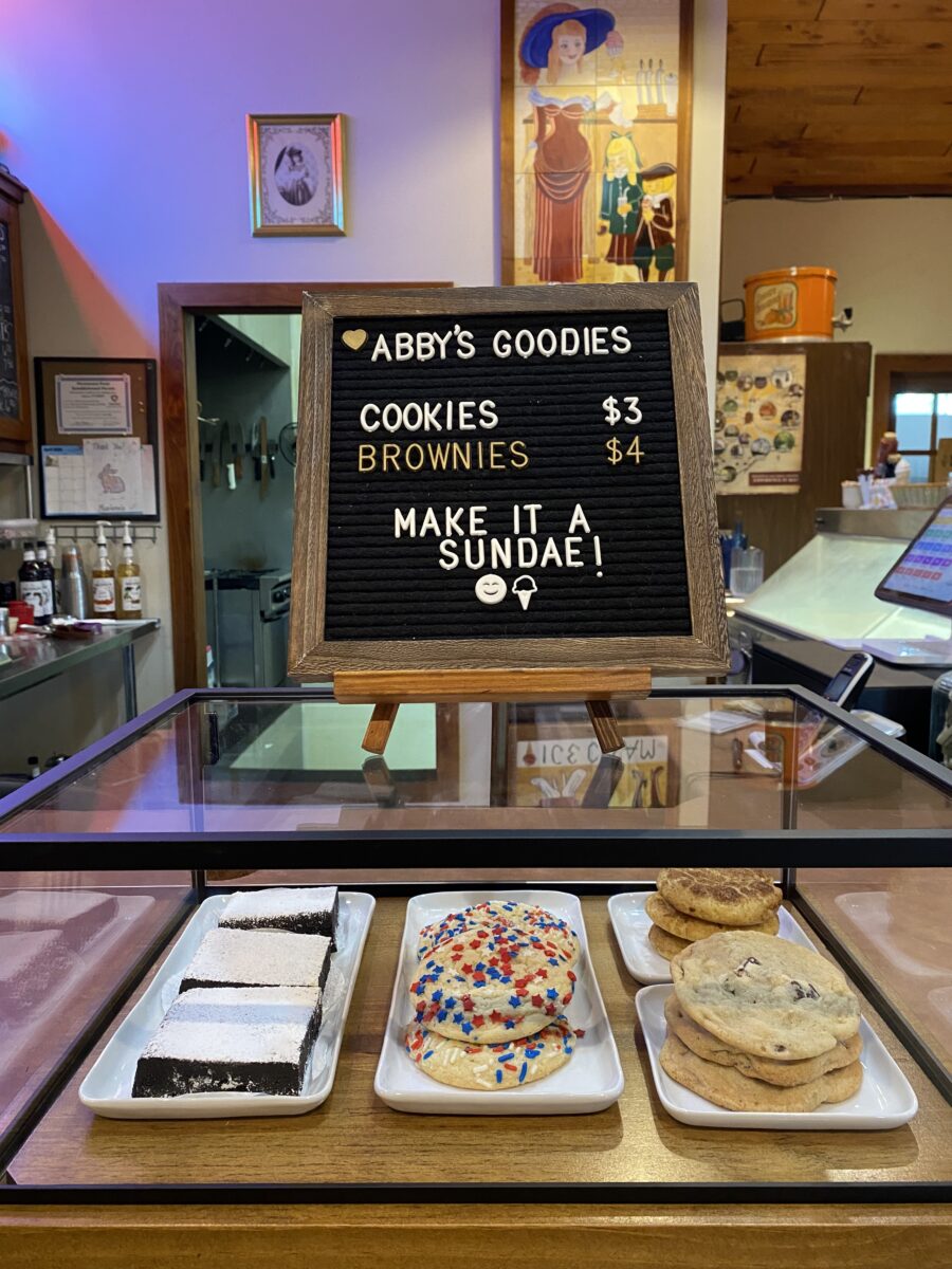 A small black sign with white text situated above pastries.