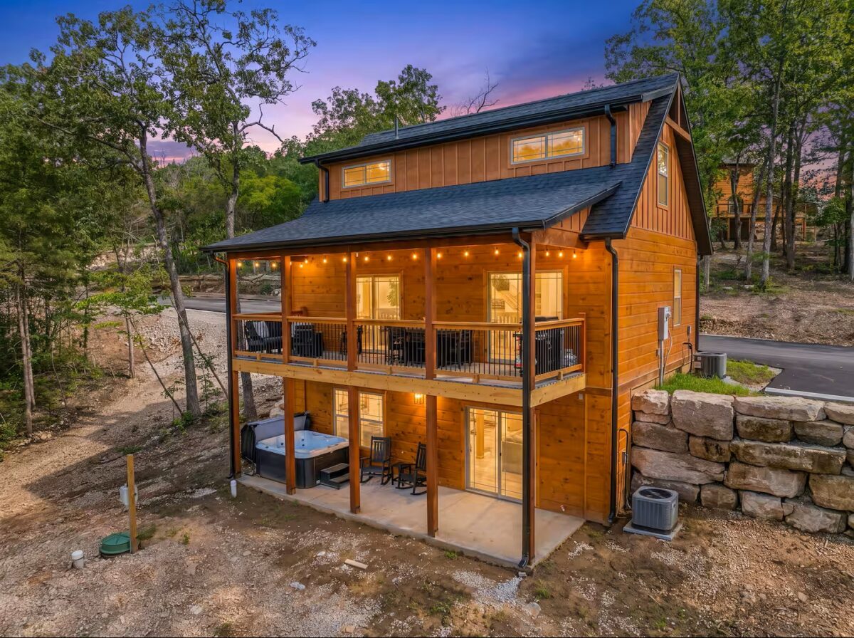 Plaid Fox back exterior featuring three stories, rustic siding and lights.