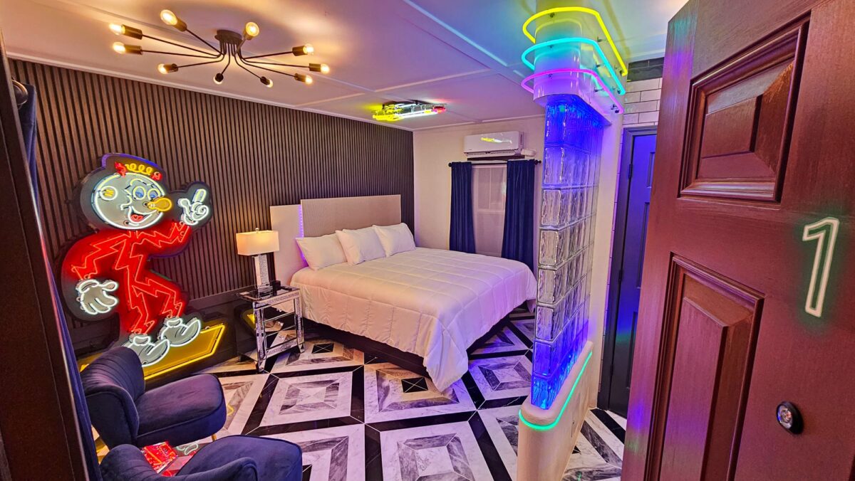 Neon-themed guest room with a bed and colorful Route 66 lighting at Shamrock Court Motel