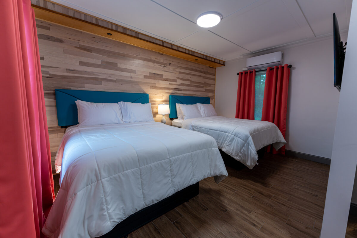 Guest room with two beds, blue headboards and red curtains at Shamrock Court Motel