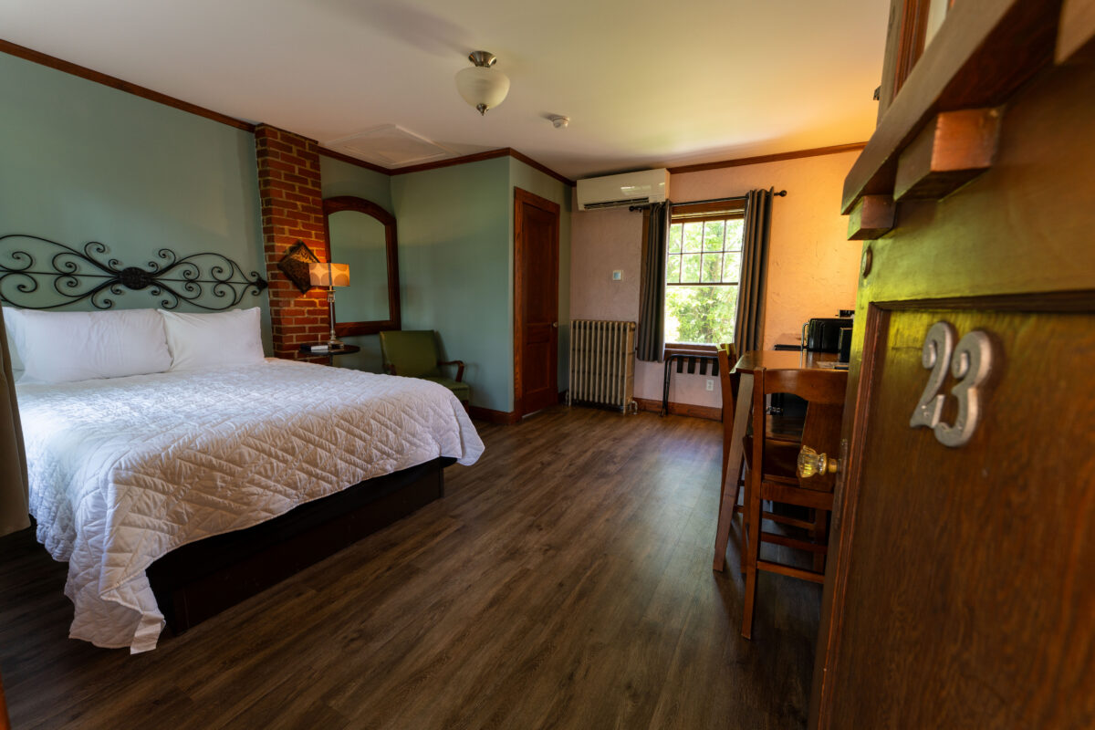 Restored queen guest room with original brickwork and wood trim at the Wagon Wheel Motel