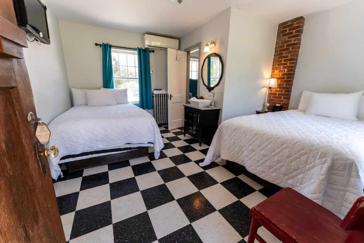 Restored two-bed guest room with black-and-white floor at the Wagon Wheel Motel