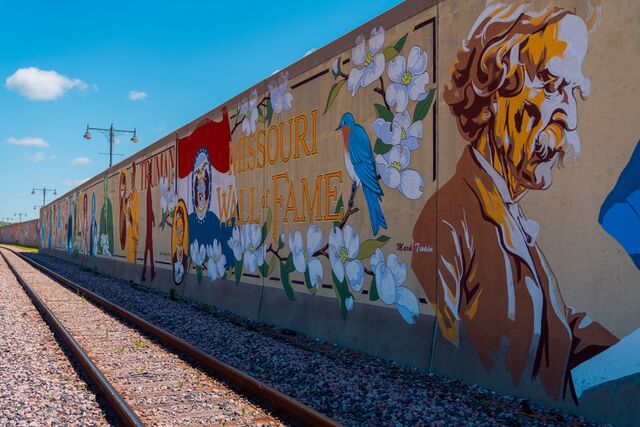 A mural on a wall features a painting of Mark Twain, the Missouri flag, a bluebird and dogwood flowers.